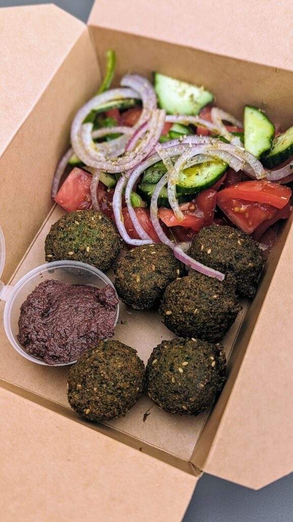 a small brown box filled with six vegan falafel balls and a small salad in santorini at falafeland