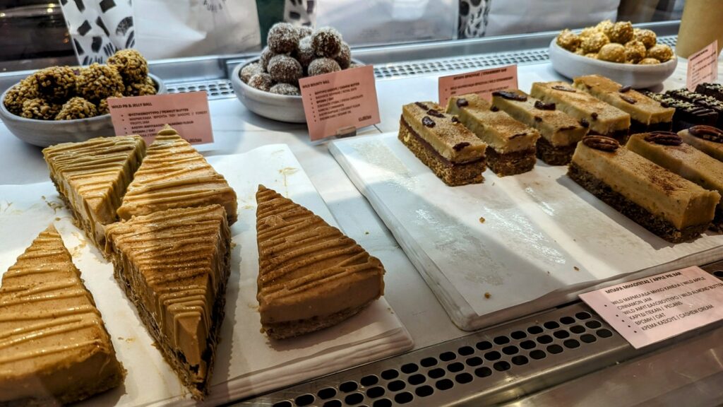 the dessert case with vegan cheesecake slices and nut bars at wild souls in athens greece