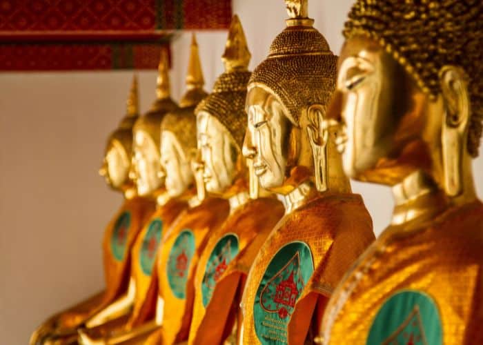 a row of golden buddha faces in a temple in thailand