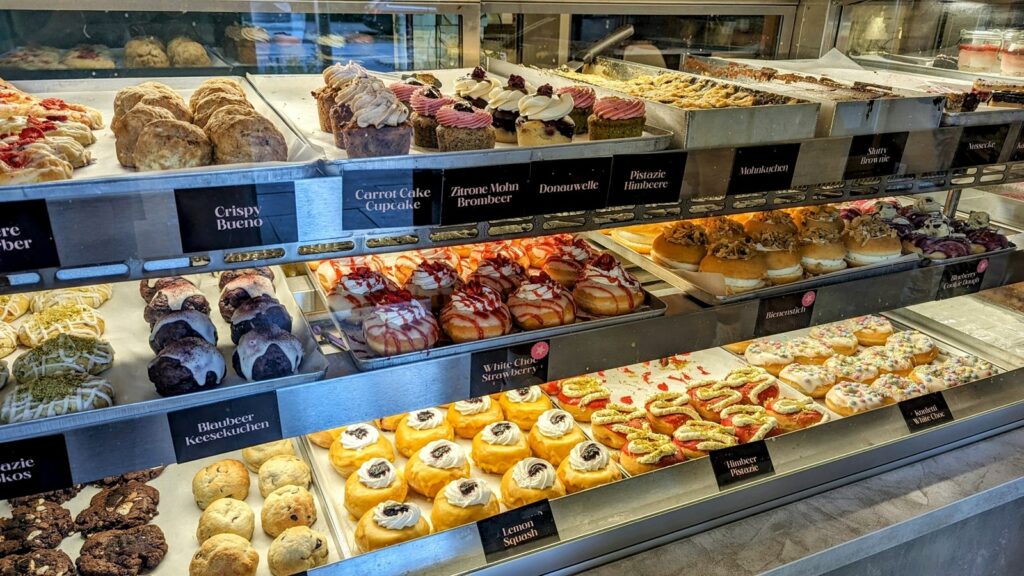 a dessert case filled with colorful vegan donuts all in rows at kjeks in hamburg