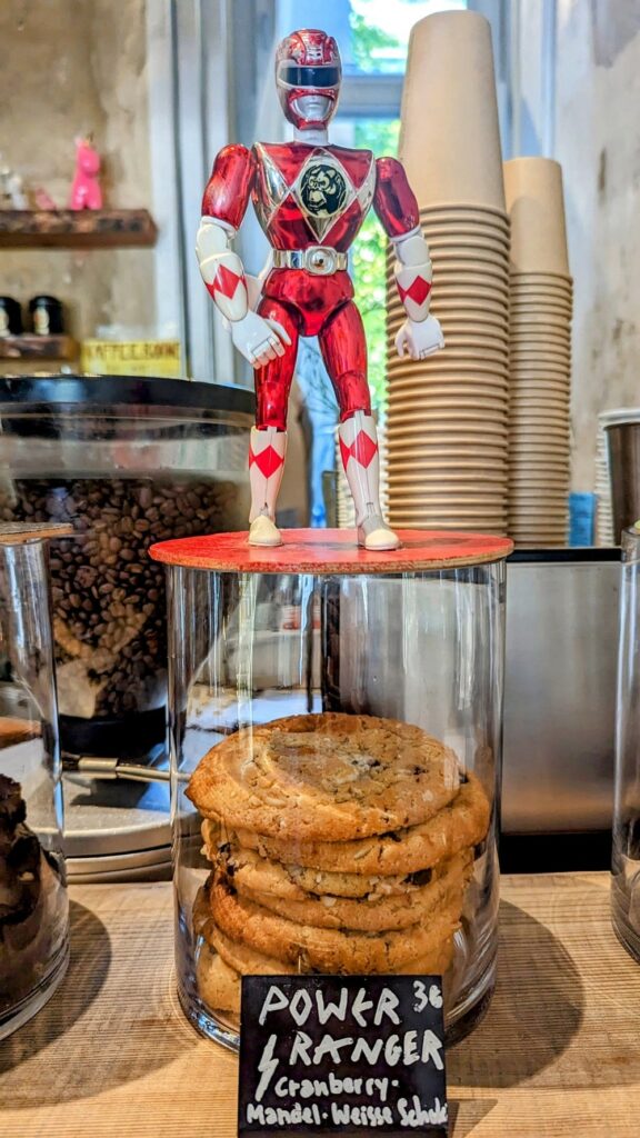 a tall round clear cookie jar with a small stack of vegan cookies with a red power ranger action figure standing on top of it in hamburg