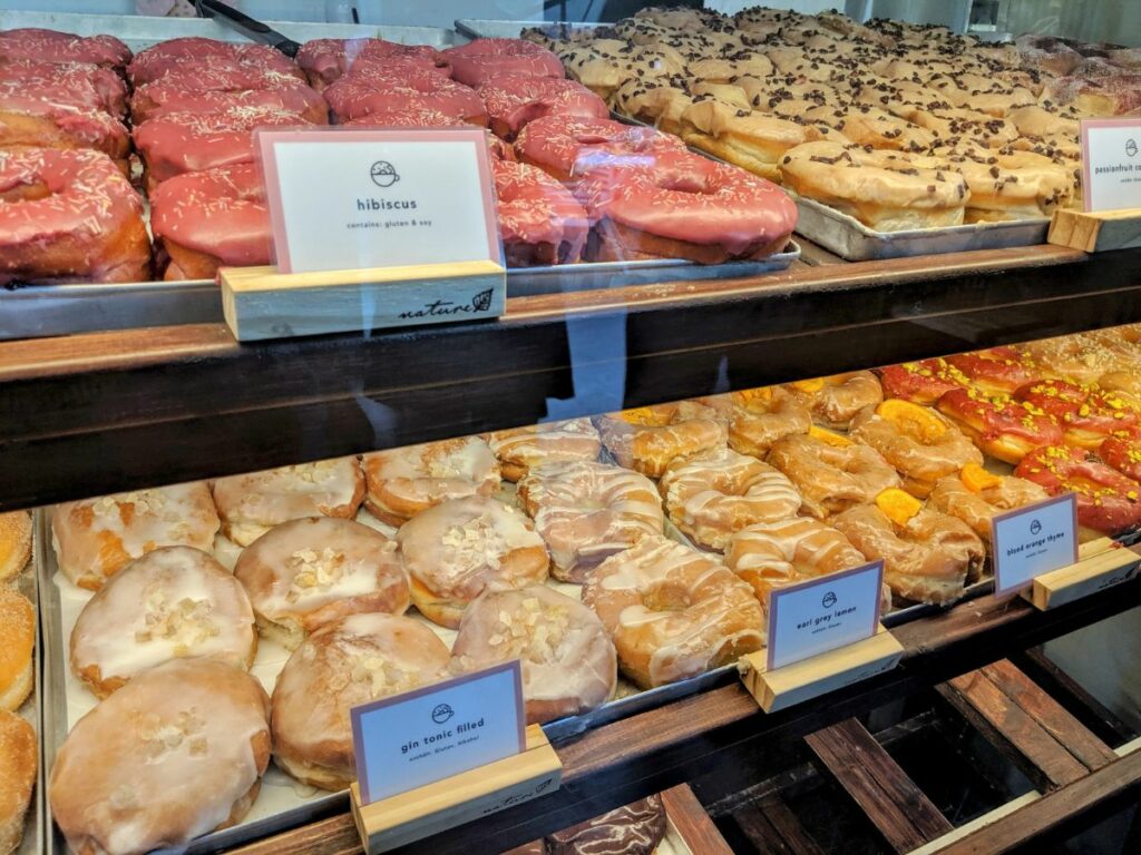 a dessert case filled with rows of colorful vegan donuts in hamburg