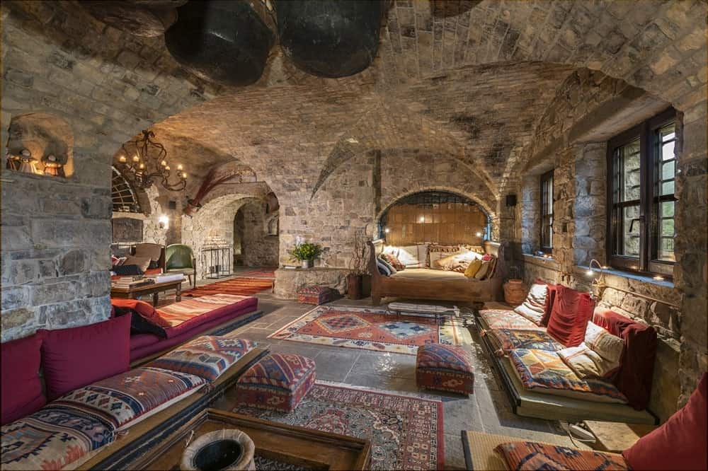 inside of the dimly lit restored monastery Eremito Hotelito Del Alma with stone walls and floor and bright red rugs and accents in italy