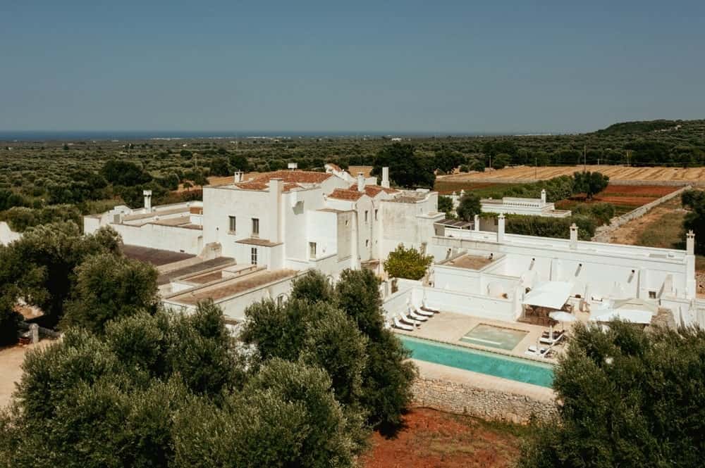 overhead view of the white stone b and b Masseria Le Carrube with a pool in the lush green italian countryside