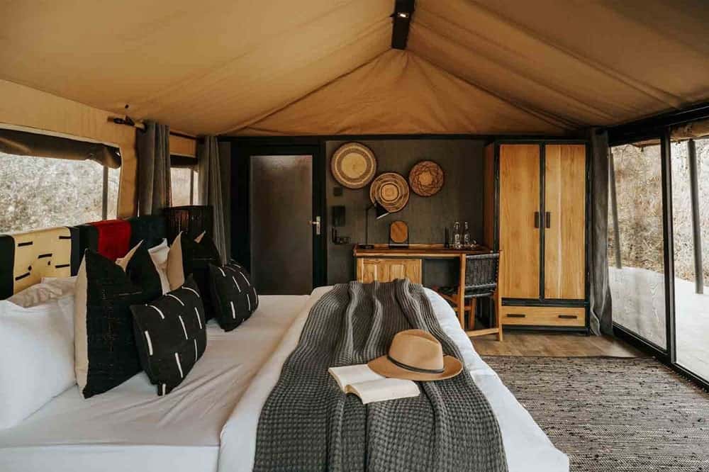 the inside of a luxury tented guest room with a large white bed at Nimali Tarangir in africa