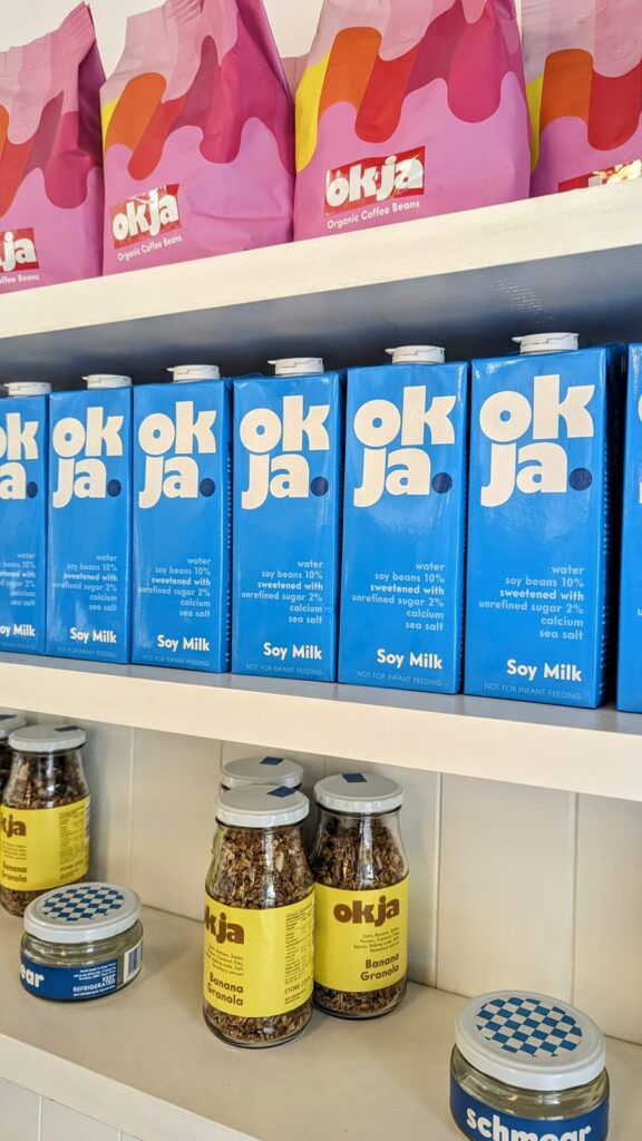 a shelf filled with blue cartons of plant based milk and coffee  okja in cape town