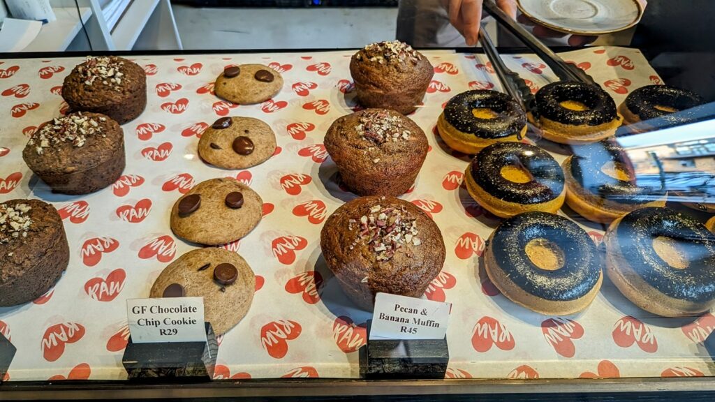 a dessert case with rows of vegan donuts, cookies, and muffins at Scheckters Raw  in cape town