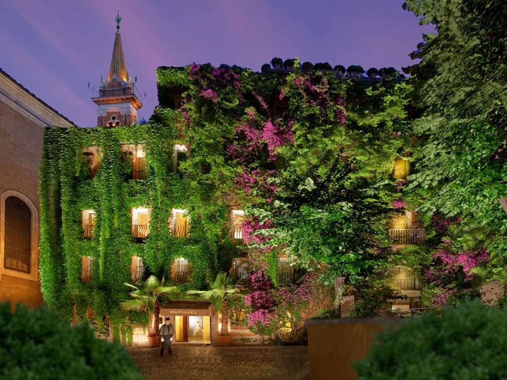 ivy covered building at night with the soft golden glow of light from inside the hotel rooms at bio hotel raphael in rome