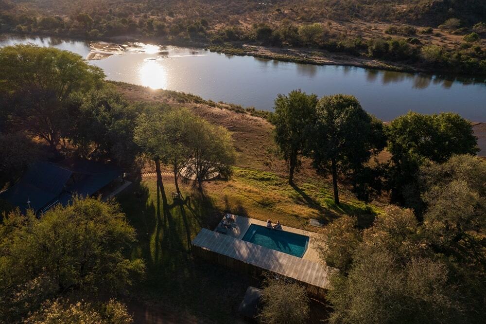 overhead view of the vegan safari camp sashwa river of stars at dusk with the sun setting over the nearby river