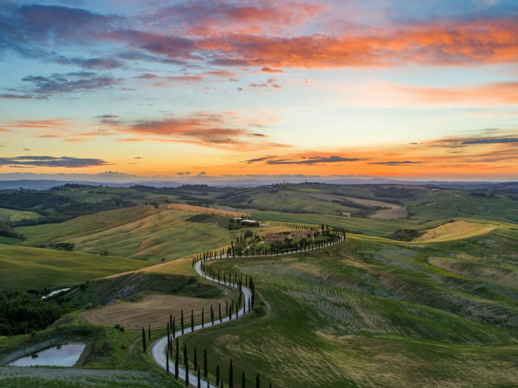 gorgeous coral and pink sunset over the lush green hills of tuscany