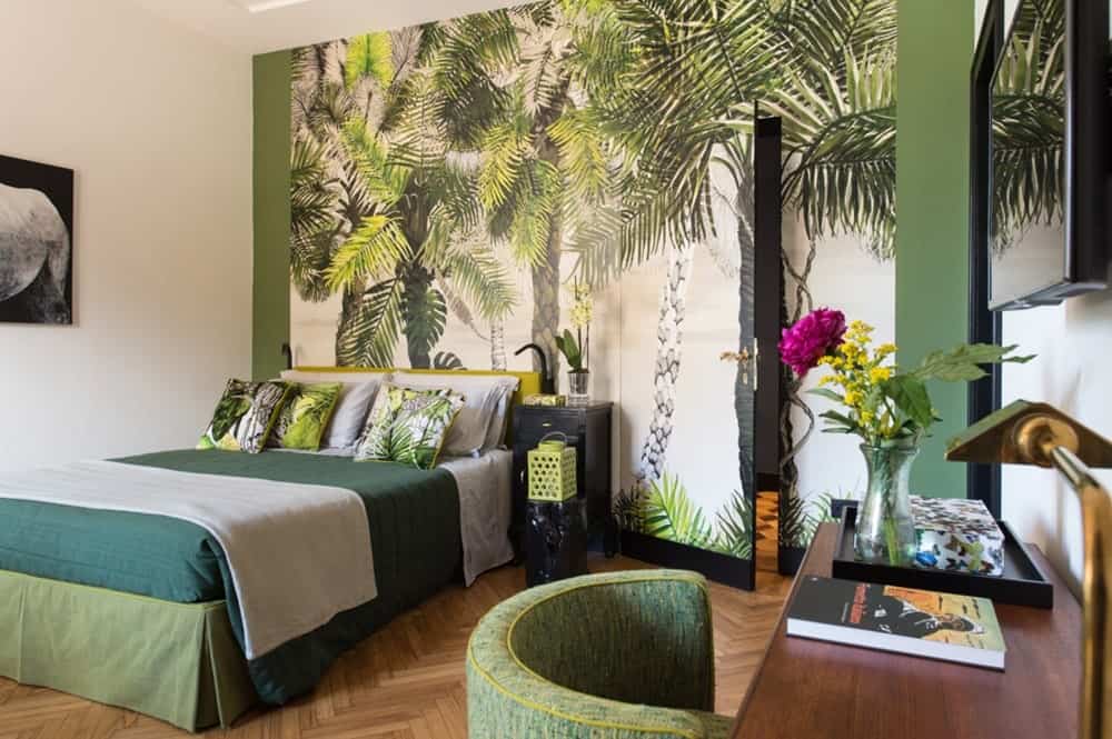 a jungle themed guest room with palm tree inspired wallpaper and green bedding at velona's jungle suites in florence