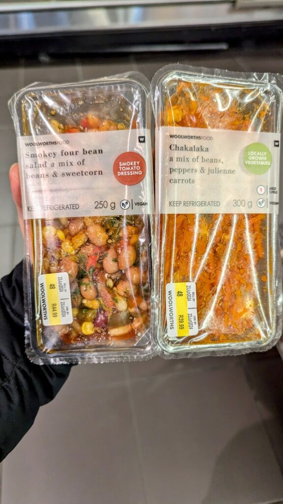 two vegan packaged salads held in one hand at woolworths in cape town