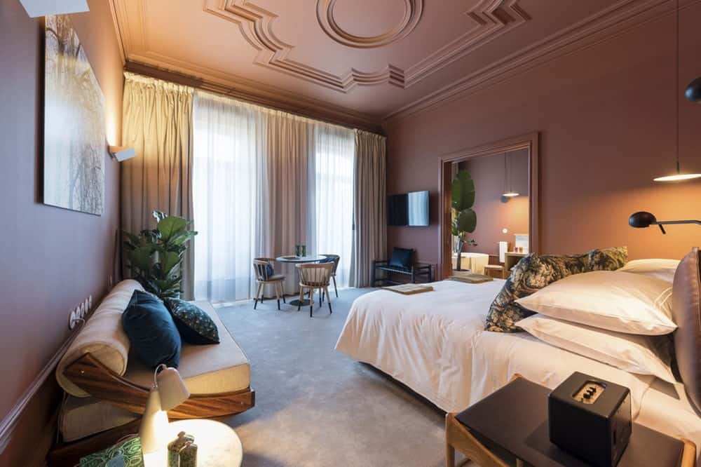 sophisticated and elegant guestroom with a decorative pink ceiling and natural colored bedding in porto