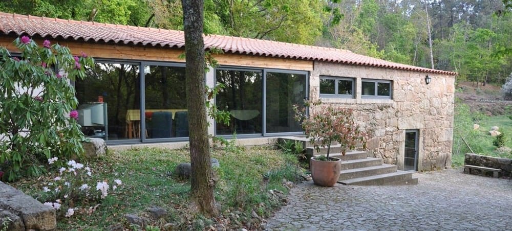 the outside of a long hotel building surrounded by forest with large window in portugal