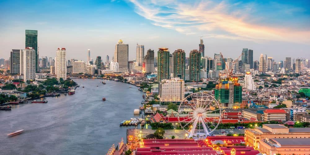 overhead view of bangkok with the river and ferris wheel in the foreground surrounded by tall buildings