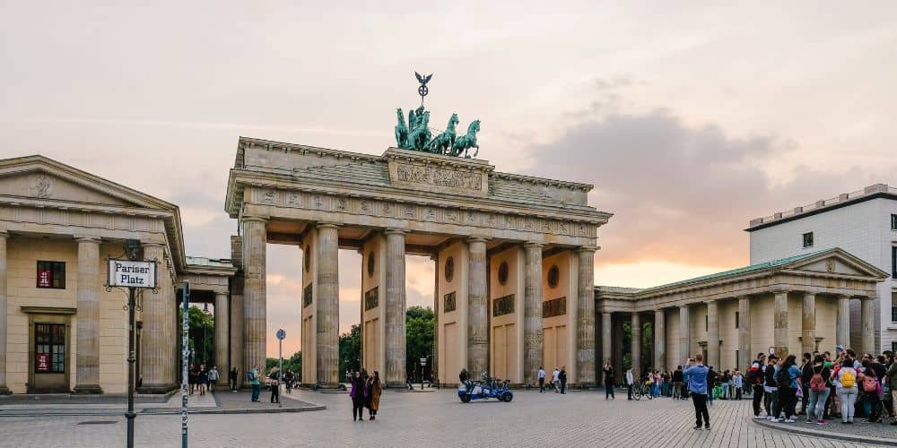 the brandenburg gate on a partly cloudy day with only a few people around it in berlin