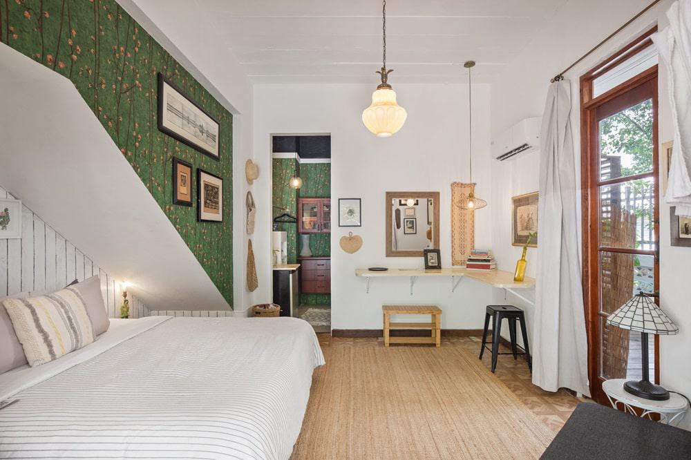 the garden suite with green floral wallpaper and white bedding and walls at la botanica vegan hotel in puerto rico