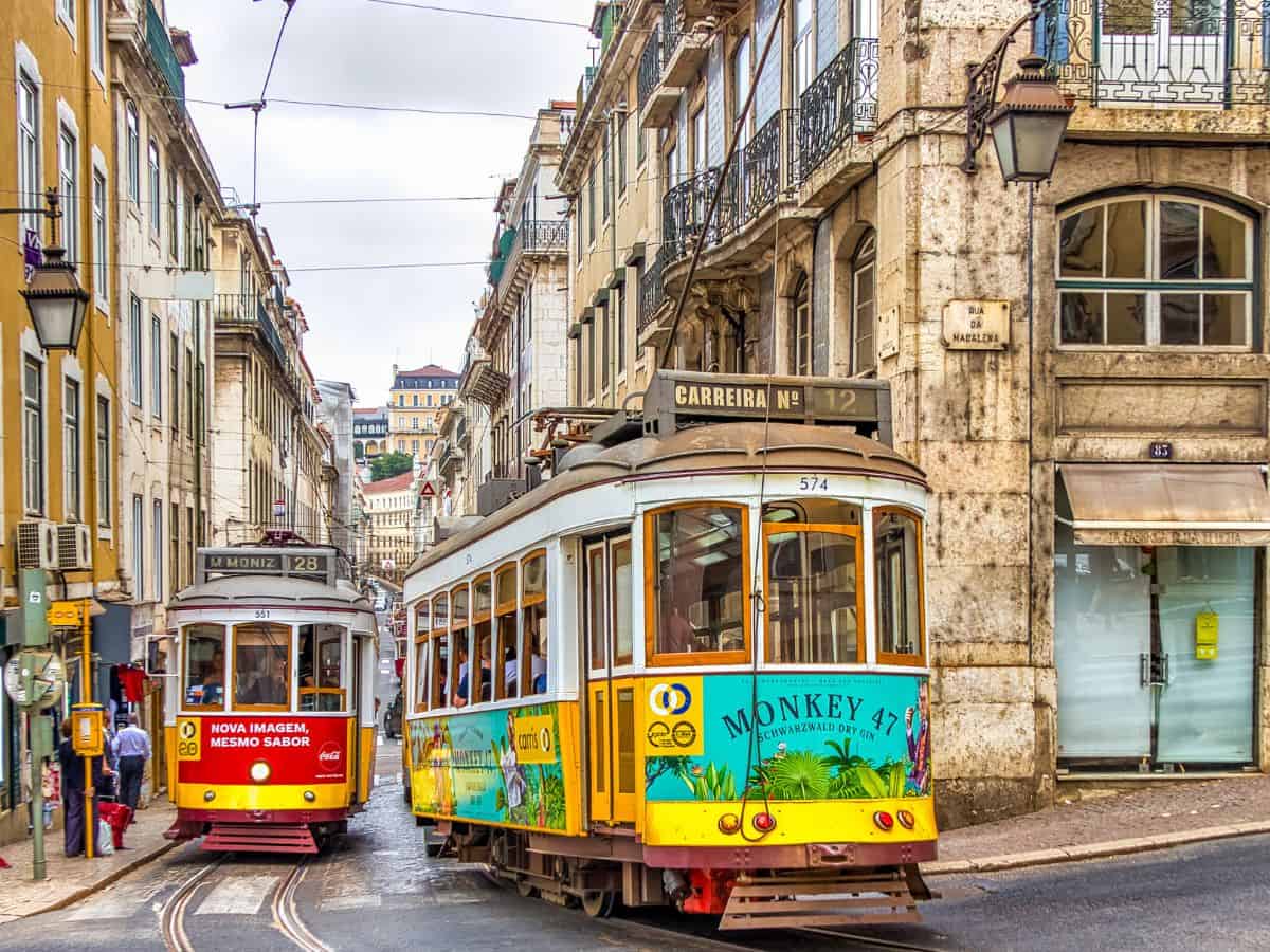 two colorful vintage trolleys coming down the street in lisbon, portugal