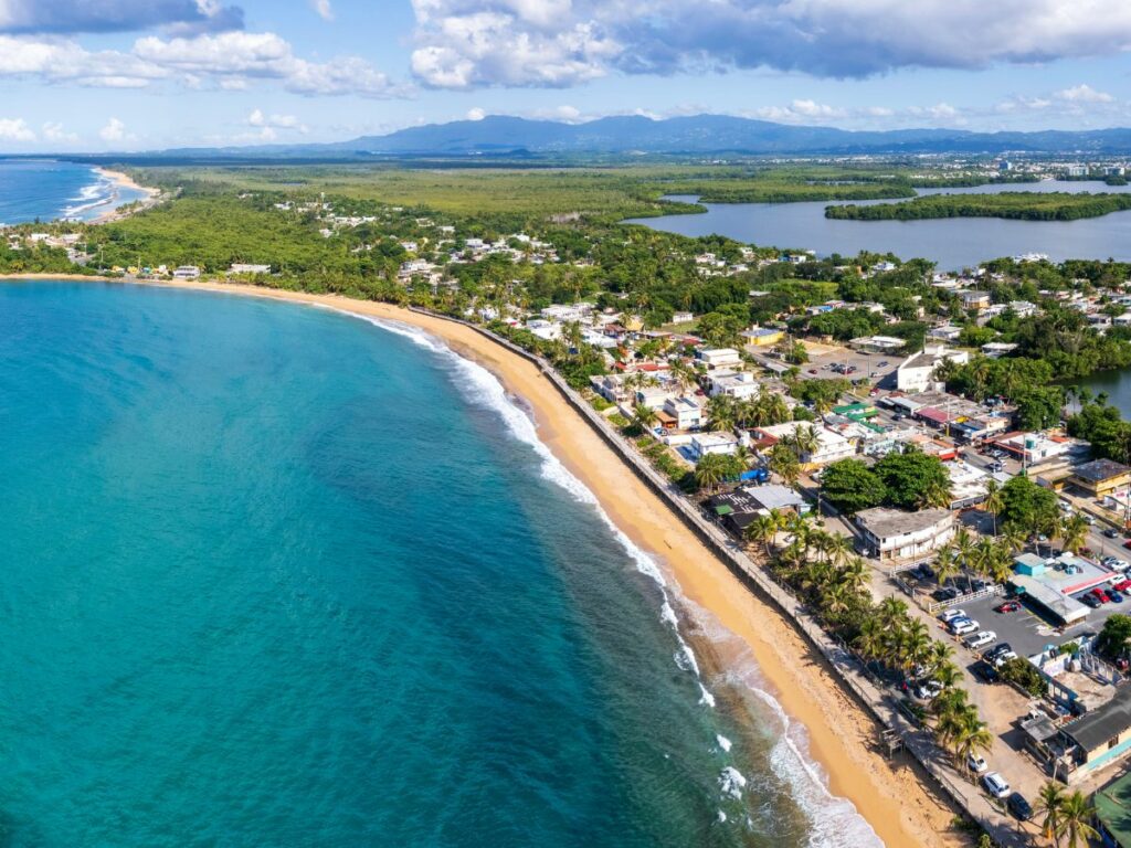 overhead shot of the turquoise waters, beach, city, and lush green jungle that makes up the island of puerto rico