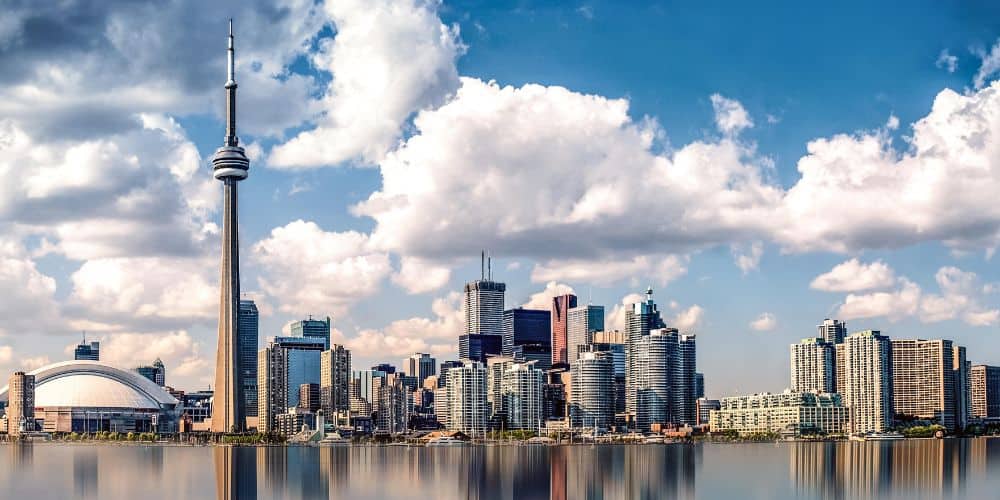 the toronto skyline on a clear day with a few puffy clouds with the tall cn tower off to the side, taken from toronto islands