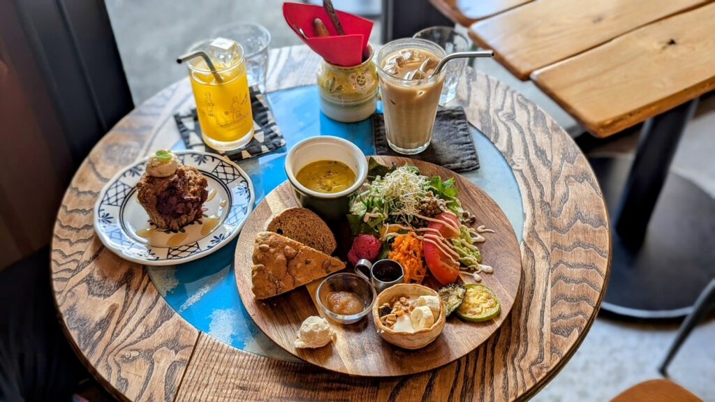 a round bistro table filled with a giant round platter of vegan breakfast treats like muffins, scones, granola and yogurt at Café Phalam in kyoto