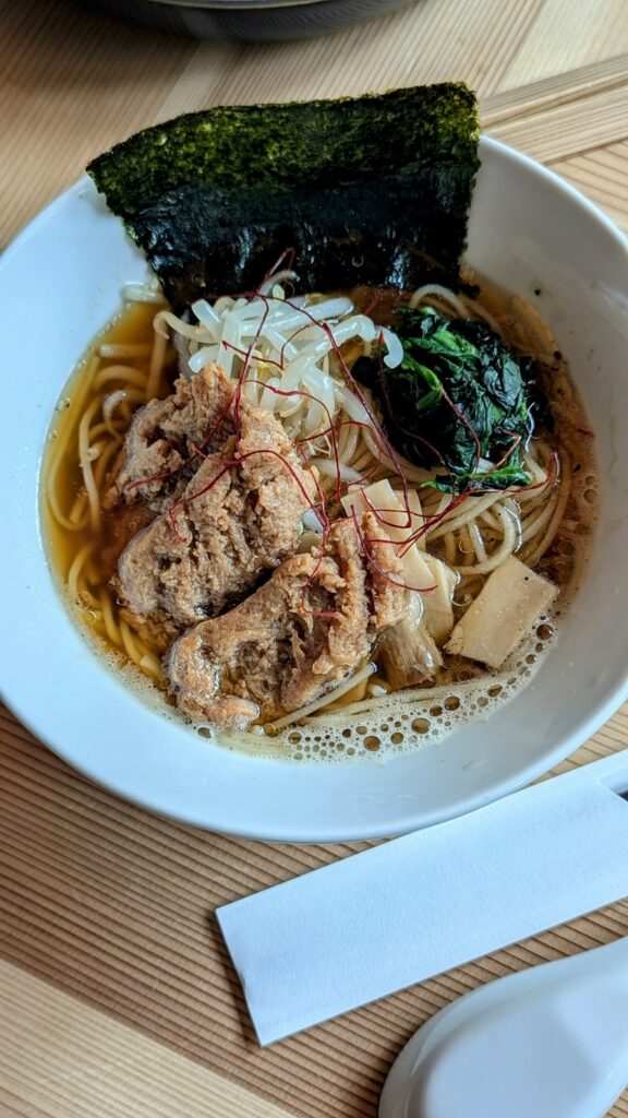 a large white bowl of vegan and gluten free ramen with tofu and seaweed at cafe tea terrace in kyoto