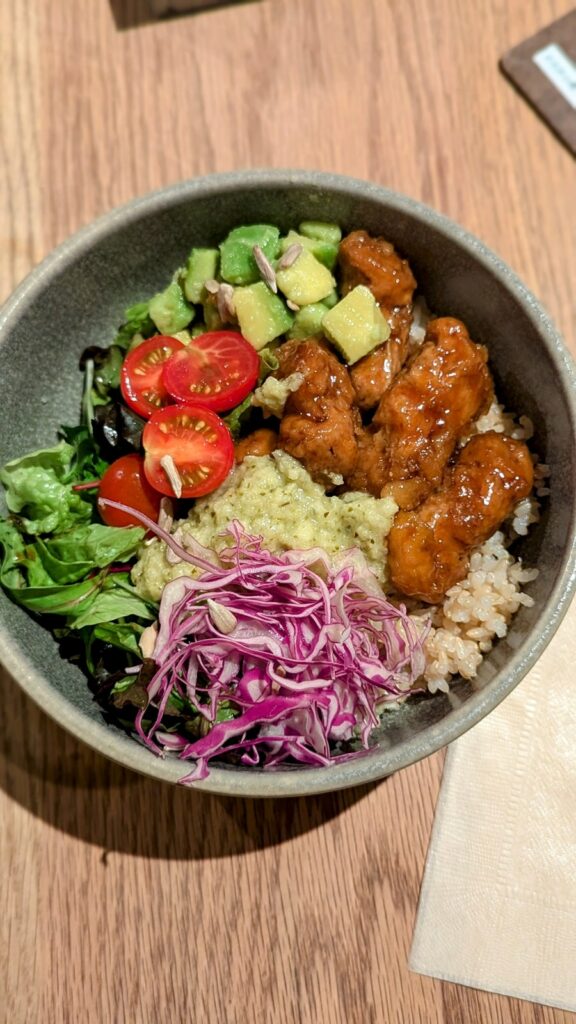 a round bowl filled with golden fried vegan chicken called karaage in japan with rice and veggies at cosme kitchen adaptation  in tokyo