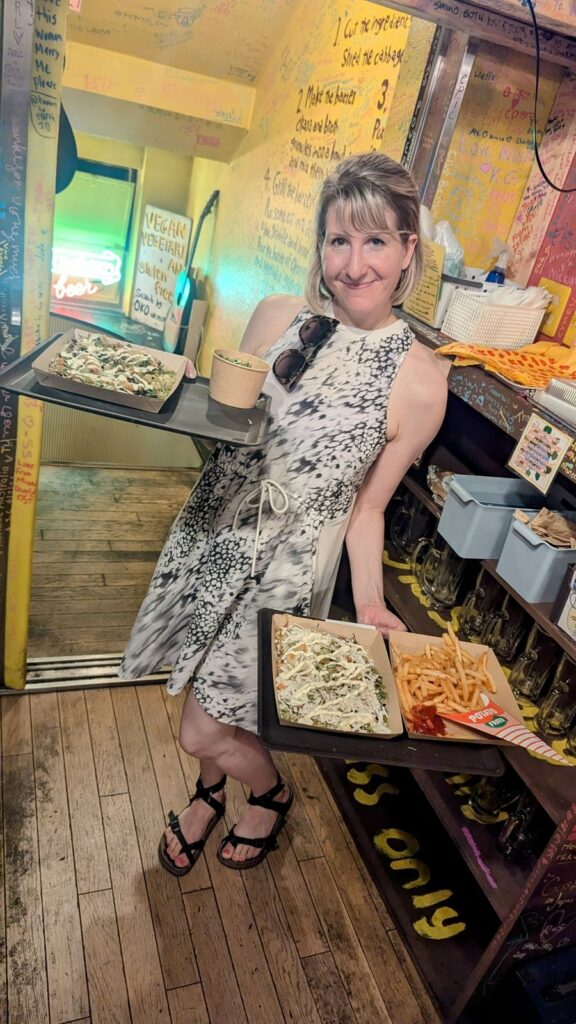 rebecca gade sawicki holding two orders of vegan okonomiyaki inside of the eccentric vegan spot OKO-Fun Okonomiyaki Bar in osaka