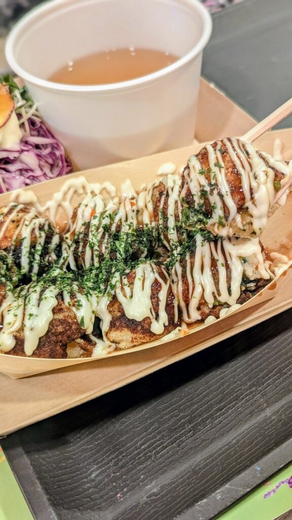 up close view of a vegan takoyaki held in chopsticks covered with a white cream sauce at OKO Takoyaki in osaka