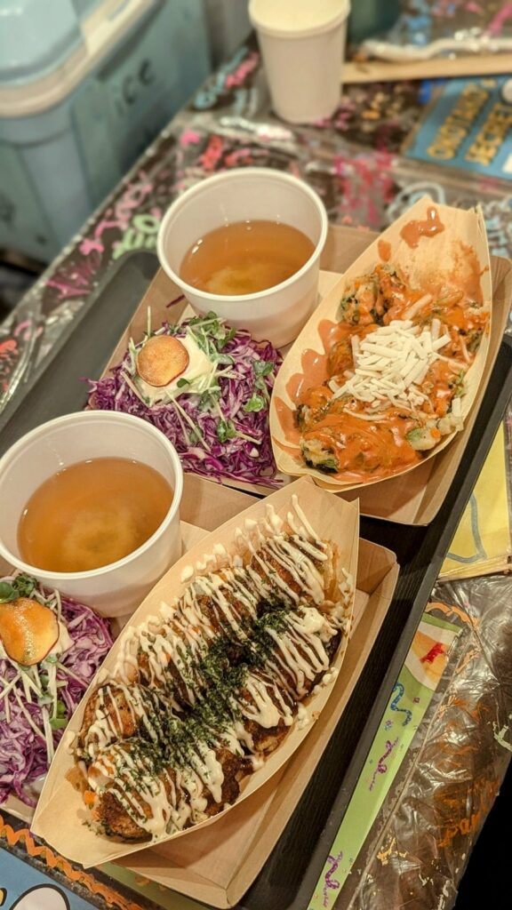 two orders of vegan takoyaki next to each other with two bowls of miso on a colorful graffiti covered table at OKO Takoyaki 