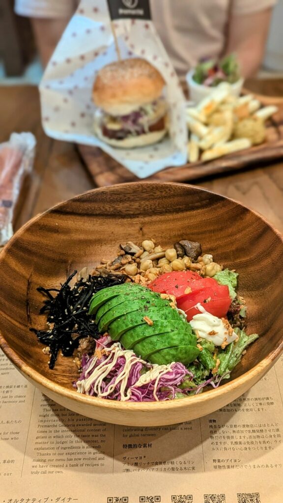 a vegan salad with cut avocado on top in a round wood bowl at Premarché Alternative Diner in kyoto