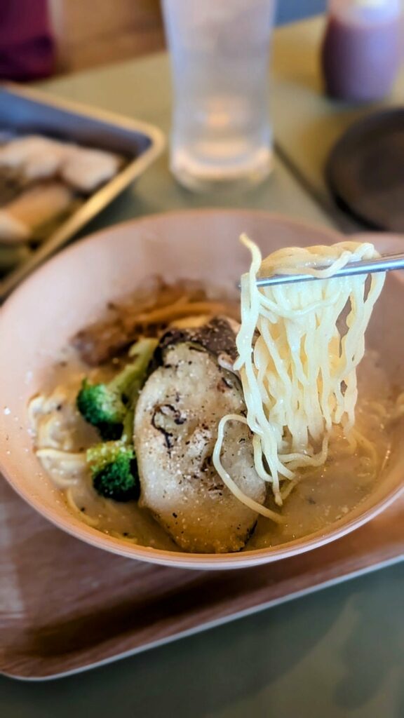 upclose view of a bowl of vegan ramen with chopsticks taking out a bunch of noodles at Shinsekai Paprika Shokudo