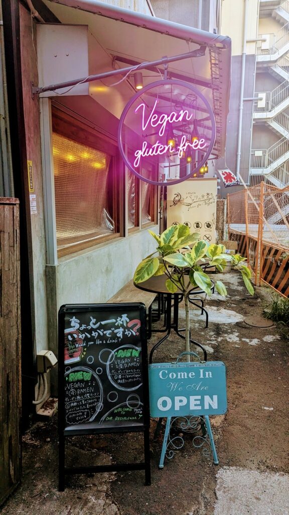 the outside of the vegan izakaya Shinsekai Paprika Shokudo with a purple neon sign that says vegan and gluten free