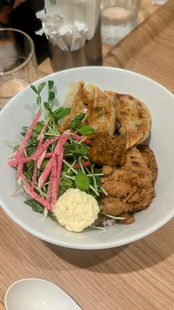 a bowl of plump vegan gyoza with greens and pickled veggies at t's tan tan in tokyo station