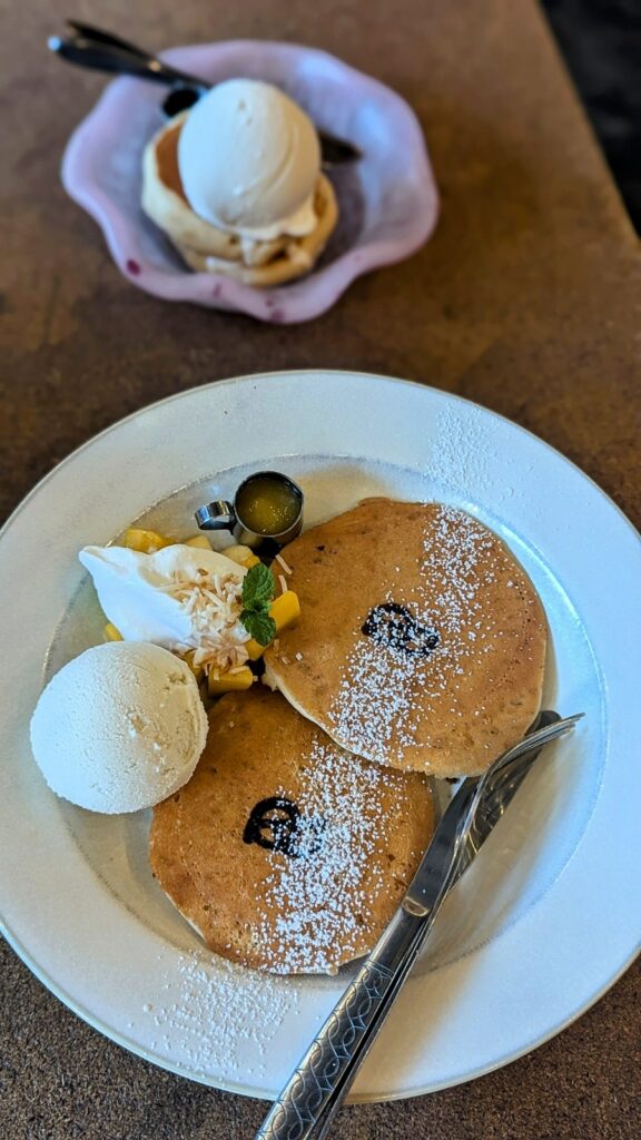 two american style pancakes with sliced mango and ice cream on a white plate at cafe pqs