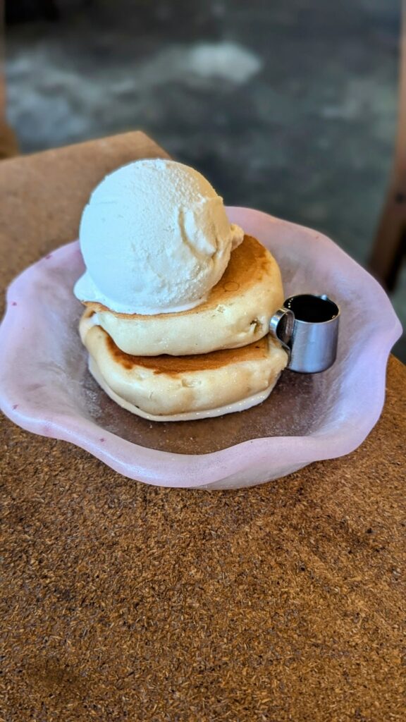 a mini stack of two fluffy vegan pancakes topped with a single scoop of vanilla ice cream at vegan cafe pqs in tokyo