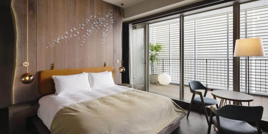 bright and modern guest suite with large floor to ceiling windows and natural wood at the good nature hotel in kyoto