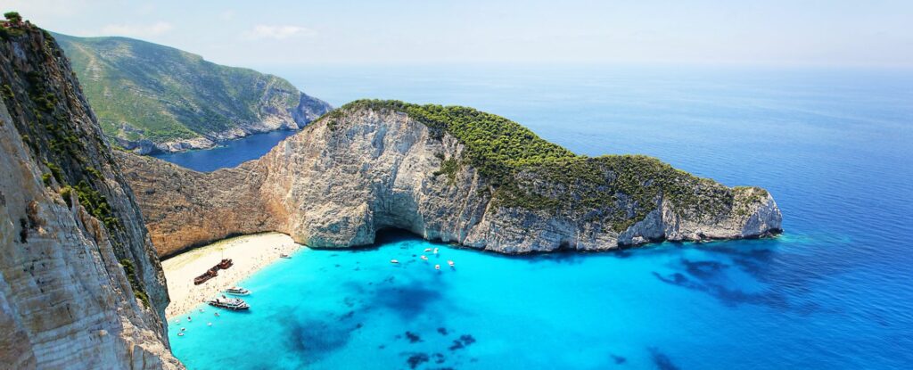 overhead shot of a hidden white sand beach on the coast of a greek island surrounded by turquoise water