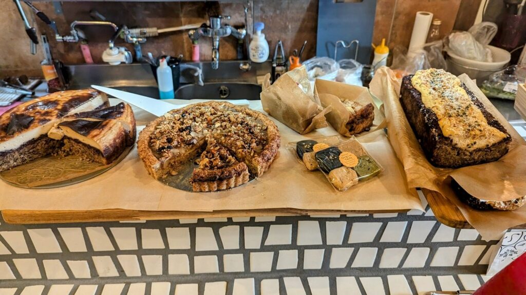 a white tiled countertop covered with a variety of vegan cakes, cheese cakes, and breads at re public by base island kitchen in osaka 