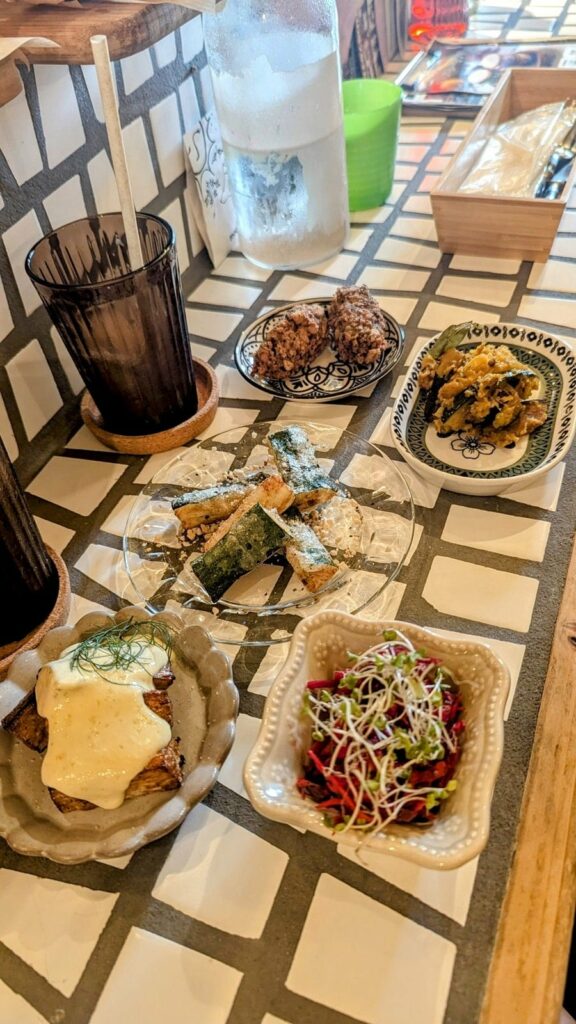 five small vegan tapas style dishes spread across a white tiled counter at re public by base island kitchen in osaka