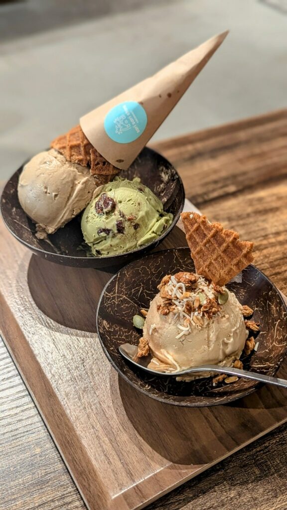 two black ice cream bowls one filled with on scoop of vanilla ice cream, topped with waflle cone pieces and the other with a scoop of coffee and green moringa ice cream topped with a full golden waffle cone at sari sari on osaka