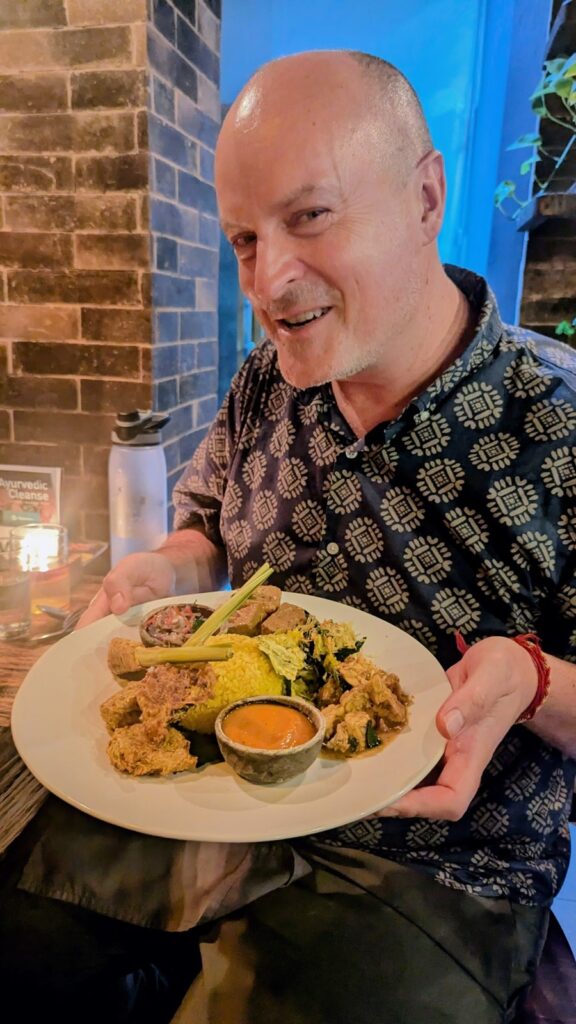 matthew kessie holding a plate of vegan nasi campur in the dining room of dapur usada in ubud