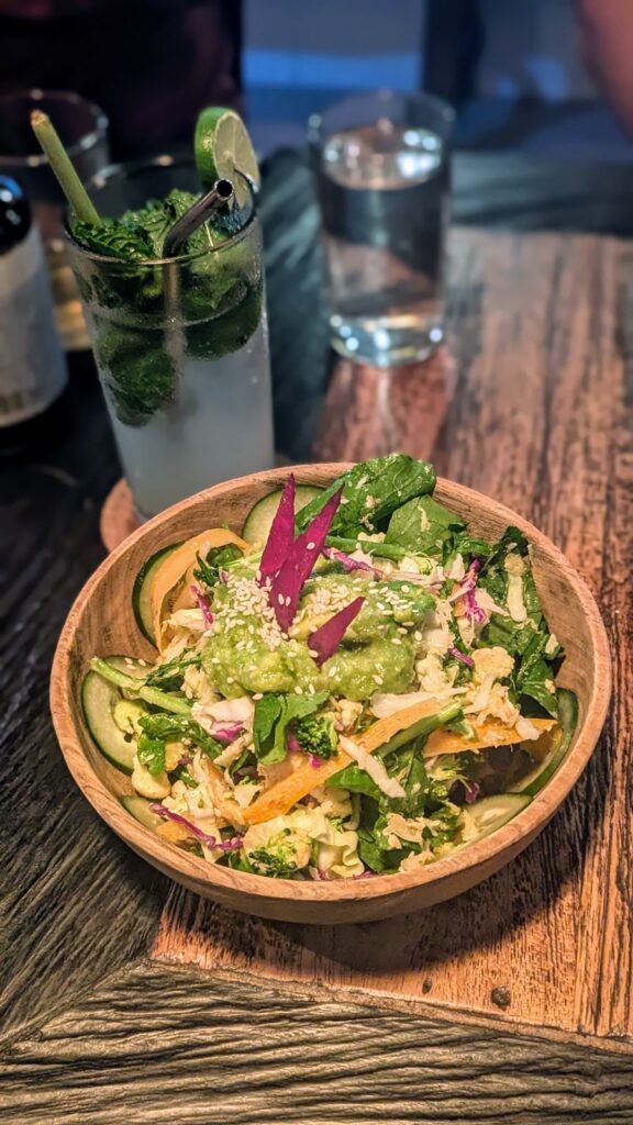 a colorful vegan salad bowl next to a cold herbal drink at dapur usada in ubud