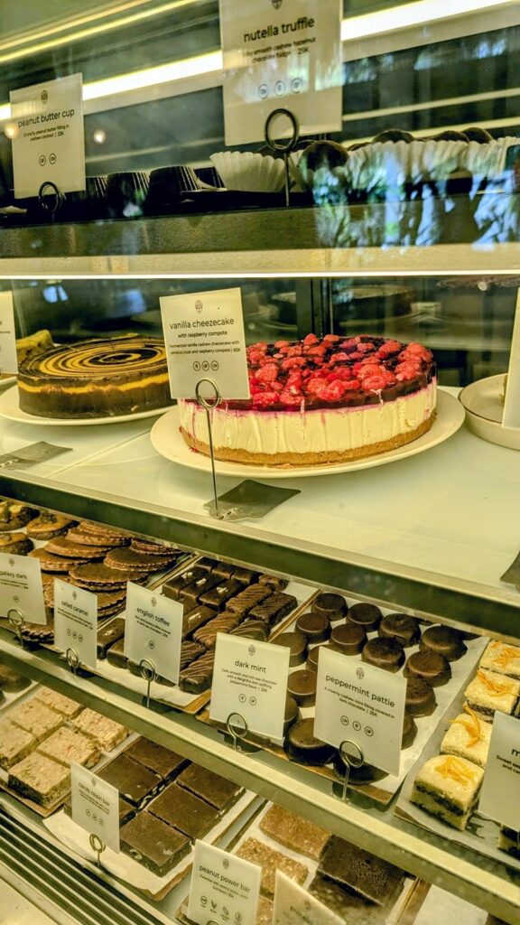 a vegan dessert display case with rows of handmade dark chocolates and one large, round cheesecake topped with fresh berries at alchemy in ubud