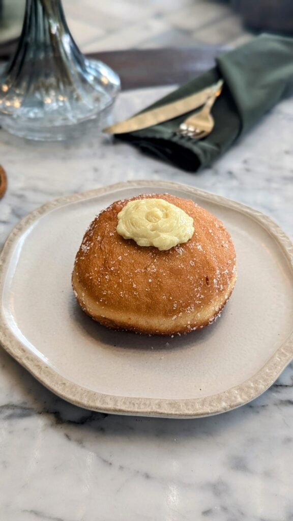 a single golden italian style vegan donut on a round white plate at plant bistro in ubud