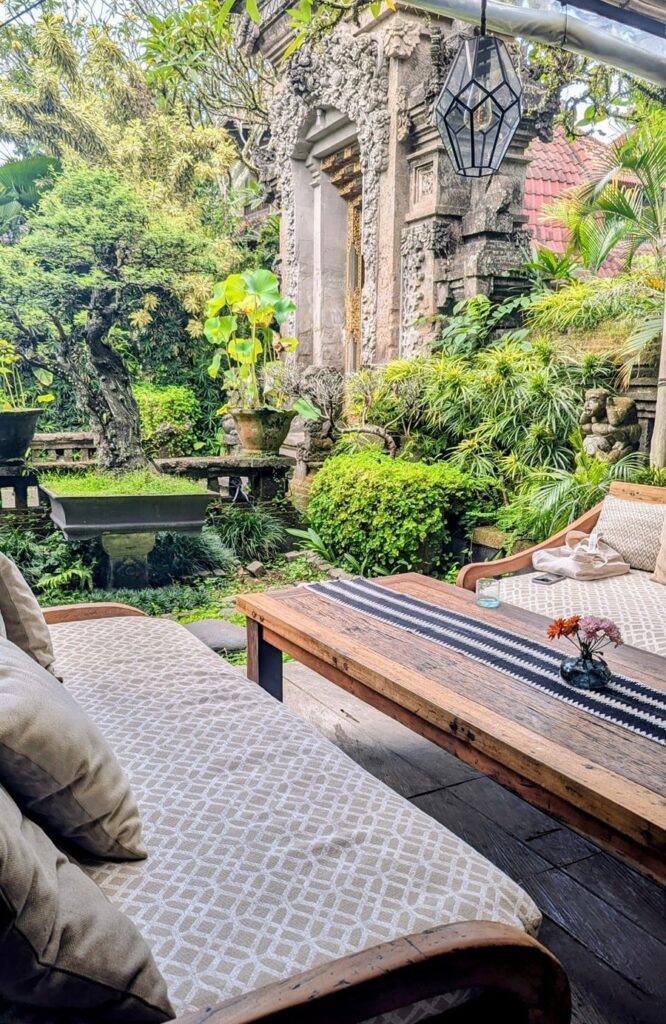 two neutral colored outdoor love seats next to a large outdoor patio with greenery and Balinese architecture at zest ubud