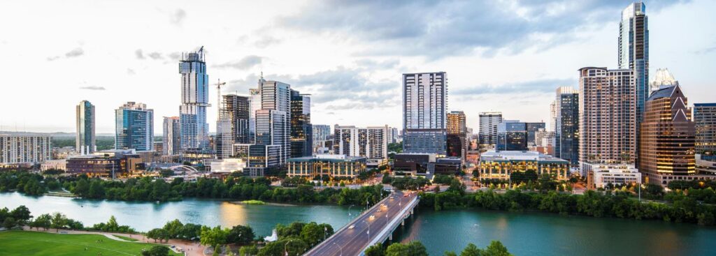 austin city skyline in front of the river on a partly cloudy day