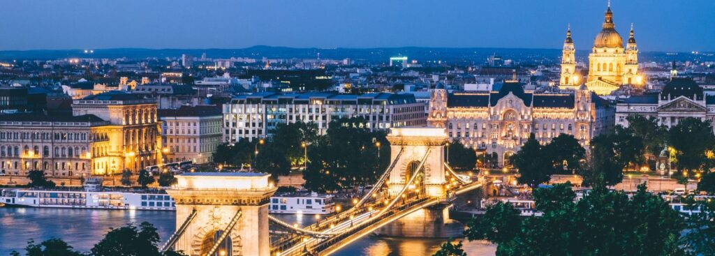 budapest chain bridge and city dimly lit at nighttime