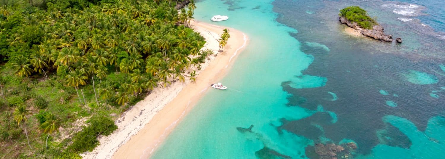 overhead shot of a secluded white sand beach surrounded by turquoise waters in the caribbean