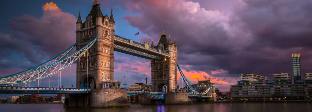 the london bridge in front of a stormy gray and purple cloud in london